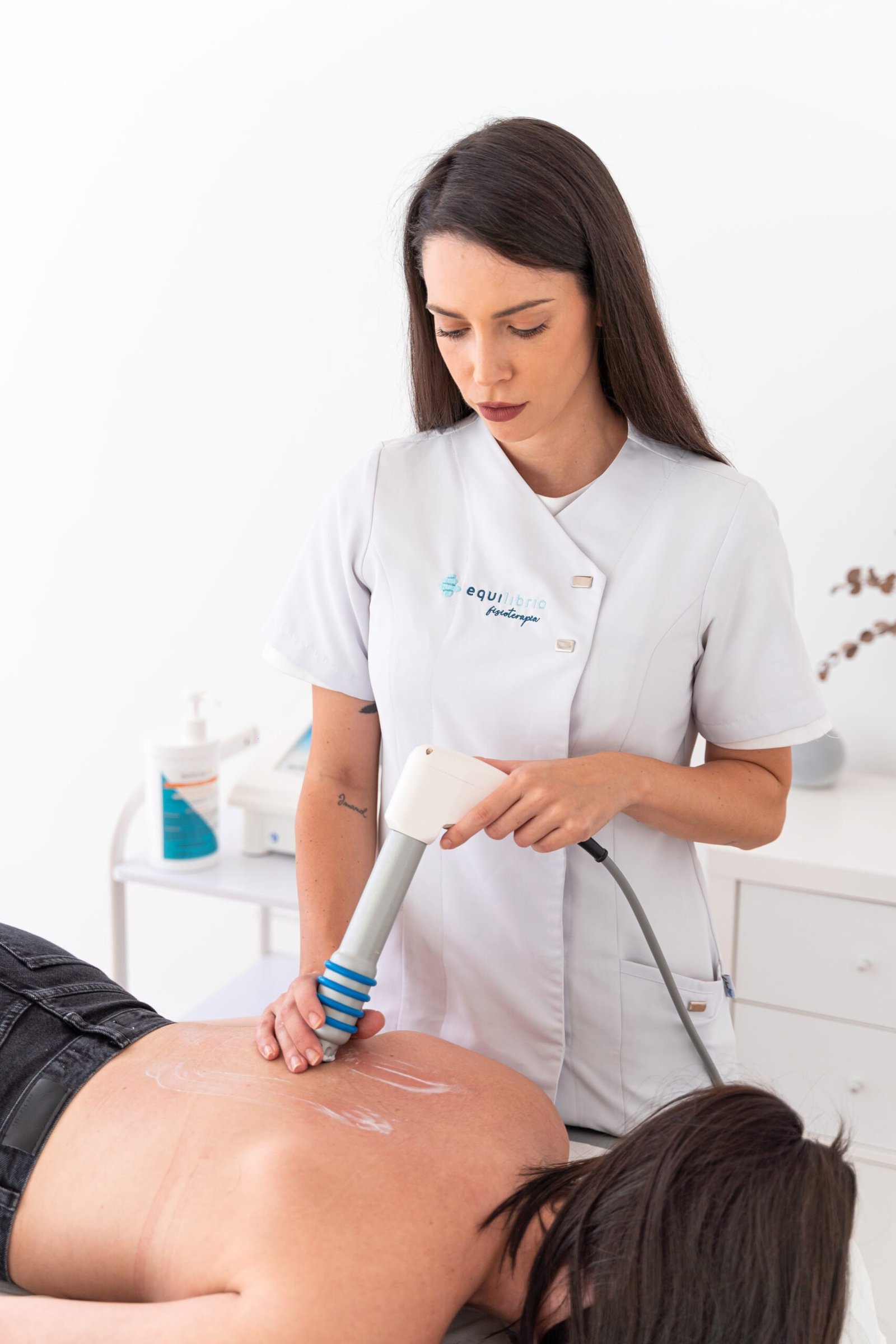 La fisioterapeuta Laura Bracero tratando la espalda de una paciente con ondas de choque.