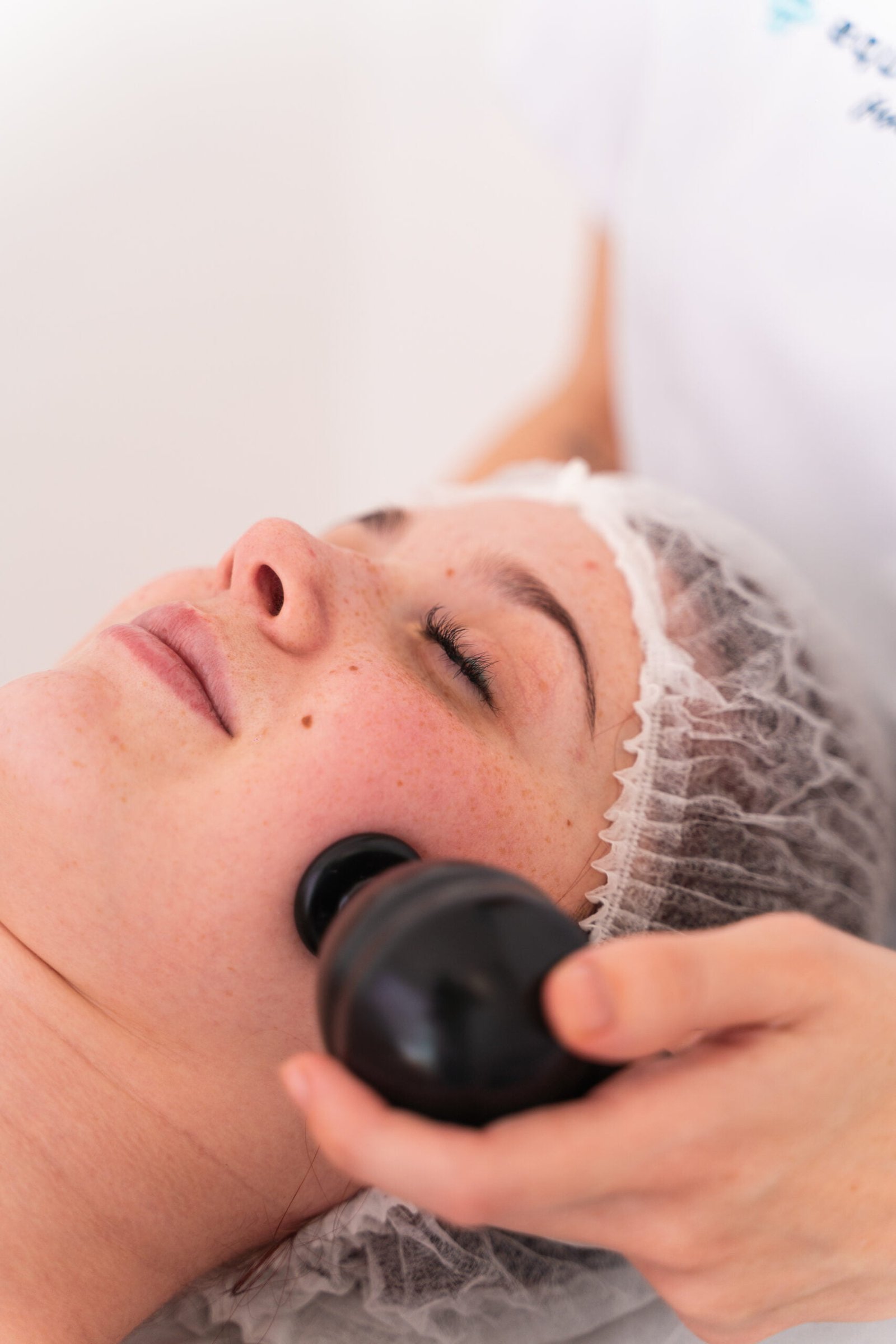 La fisioterapeuta Laura Bracero realizando fisioestética facial y aplicando la mesoterapia virtual y la diatermia sobre la piel de la cara de una paciente.