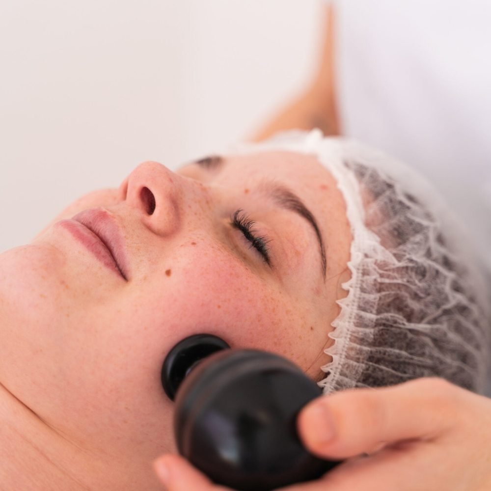 La fisioterapeuta Laura Bracero realizando fisioestética facial y aplicando la mesoterapia virtual y la diatermia sobre la piel de la cara de una paciente.