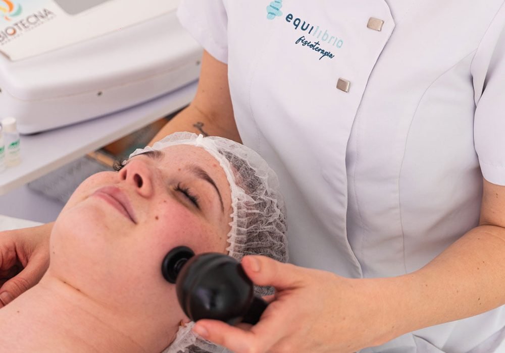 La fisioterapeuta Laura Bracero aplicando la mesoterapia virtual y la diatermia sobre la piel de la cara de una paciente.